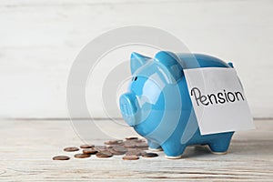Piggy bank with word PENSION and coins on table