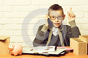 piggy pig bank holding and speaking on cell phone on white brick wall background, copy space. young cute businessboy