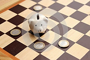Piggy piggy bank and euro coins in the form of figures on a chessboard, business concept, games