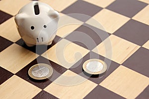 Piggy piggy bank and euro coins in the form of figures on a chessboard, business concept, games, close-up, copy space