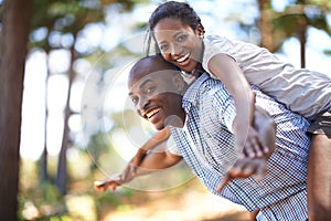 Piggyback, portrait or black couple playing in park to relax or bond on holiday vacation together to travel. Romantic