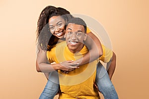 Piggyback ride. Happy african american guy carrying his girlfriend on back, black couple bonding together and smiling