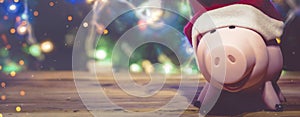 Piggybank with Santa Claus cap against decorated xmas tree. Christmas shopping. Saving money for Christmas. Pre-christmas spending