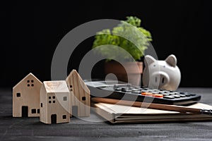 Piggybank and Small wooden houses with modern design and calculator for home loans concept