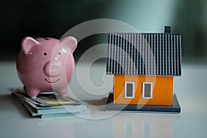 Piggybank was placed on the money and a wooden house on the table. Money-Saving Ideas for Future Home Loans Property Savings Real