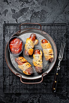 Pigs in Blanket puff pastry sausage wrap roll. Black background. Top view