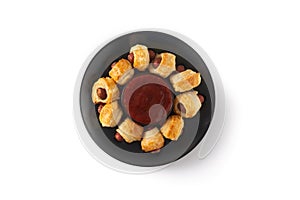 Pigs in blankets. Mini sausages wrapped in puff pastry with ketchup sauce