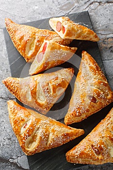 Pigs in blankets Sausage, cheese and peppers in puff pastry closeup on the marble board. Vertical top view