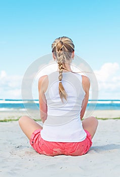 Pigtailed girl sitting on the beach.