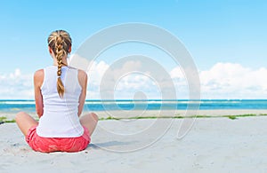 Pigtailed girl sitting on the beach.