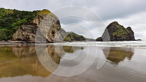 Piha black sand beach featuring cliffs and rock formations in New Zealand