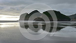 Piha black sand beach featuring cliffs and rock formations in New Zealand