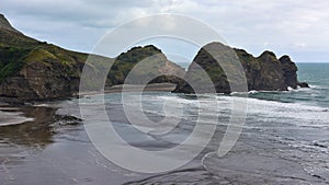 Piha black sand beach featuring cliffs and rock formations at Waitakere in New Zealand