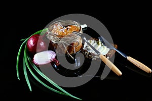 Pike caviar, roe in a glass jar, raw farm eggs, purple onion, green onions, bread with butter, fork and knife on a black backgroun