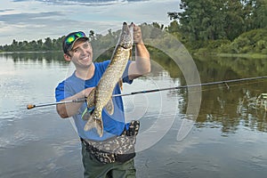 Pike fishing. Fisherman catch fish in water at river