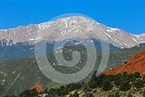 Pike`s Peak in Colorado Springs with red rocks. green trees, and blue sky