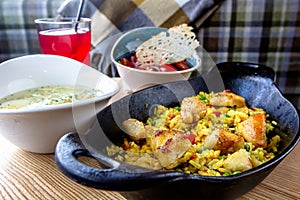 Pilaf with chicken and vegetables in a pan on a wooden table