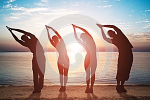 Group Of People Doing Stretching Exercise On Beach photo