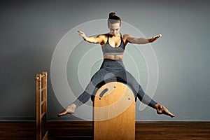 Pilates, fitness, sport, training and people concept - woman doing exercises on a small barrel. Correction of impellent