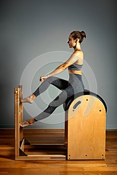 Pilates, fitness, sport, training and people concept - woman doing exercises on a small barrel. Correction of impellent