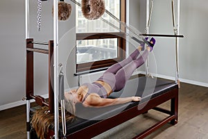 Pilates instructor on the cadilak reformer, a woman trainer in excellent shape works on a modern reformer, the study of