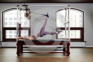 Pilates instructor on the cadilak reformer, a woman trainer in excellent shape works on a modern reformer, the study of