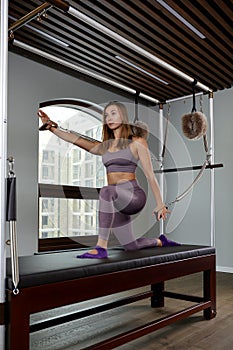Pilates instructor on the cadilak reformer, a woman trainer in excellent shape works on a modern reformer, the study of