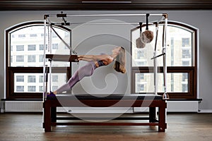 Pilates instructor on the cadilak reformer, a woman trainer in excellent shape works on a modern reformer, the study of