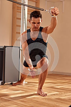 Pilates instructor performing fitness exercise on cadillac equipment, at the gym indoor.