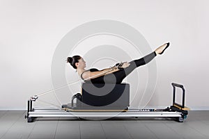 pilates machine, woman in sportswear exercising in the gym