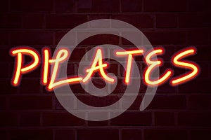 Pilates neon sign on brick wall background. Fluorescent Neon tube Sign on brickwork Business concept for Fitness Balance Workout E