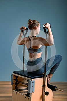 Pilates woman in a Cadillac reformer doing stretching exercises in the gym. Fitness concept, special fitness equipment