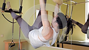 Pilates woman in cadillac split legs stretch exercise at gym