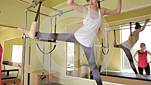 Pilates woman in cadillac split legs stretch exercise at gym