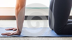 Pilates or yoga class with healthy woman kneeing on blue fitness mat working out at home in living room for healthy lifestyle photo
