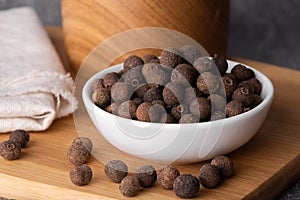 Pile of allspice isolated on white background. Jamaica pepper, allspice peppercorns or myrtle pepper in a bowl.