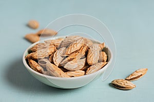 Pile of Almond nuts in a bowl on a light blue background