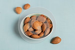 Pile of Almond nuts in a bowl on a light blue background