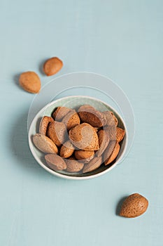 Pile of Almond nuts in a bowl on a light blue background