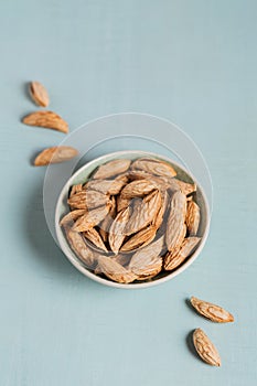 Pile of Almond nuts in a bowl on a light blue background