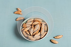 Pile of Almond nuts in a bowl on a light blue background