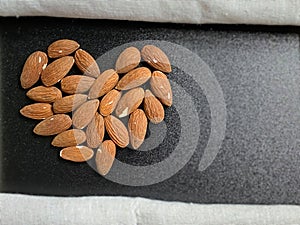 A pile of almonds in heart shape background. Healthy Eating Concept. With copy space.