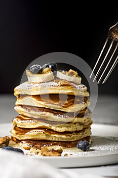 Pile of american pancakes with blueberries and bananas before eating.