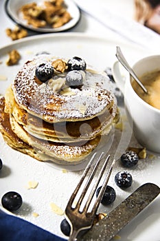 Pile of american pancakes with blueberries and powdered sugar.