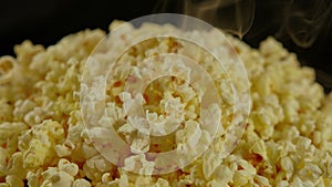 Pile of appetizing popcorn with dissipating steam. Freshly cooked hot popcorn. Close up. Concept of snack for movie.