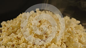 Pile of appetizing popcorn with dissipating steam. Freshly cooked hot popcorn. Close up. Concept of snack for movie.