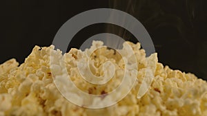 Pile of appetizing popcorn with dissipating steam. Woman's hand takes freshly cooked hot popcorn. Close up