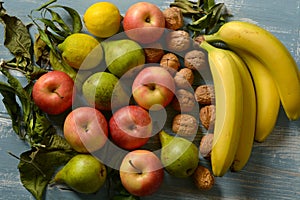 Pile of apples, pears, walnuts and bananas on light blue wooden table
