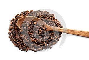 Pile of aromatic dry cloves and wooden spoon on white background, above view