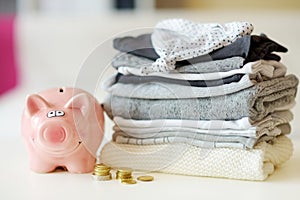 A pile of baby clothes, coins and a piggy bank. Parenting expenses concept. Working out a baby budget. Saving money when planning